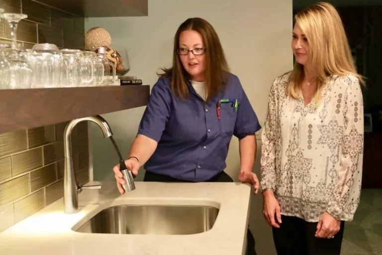 Female plumber explaining sink issue to homeowner.